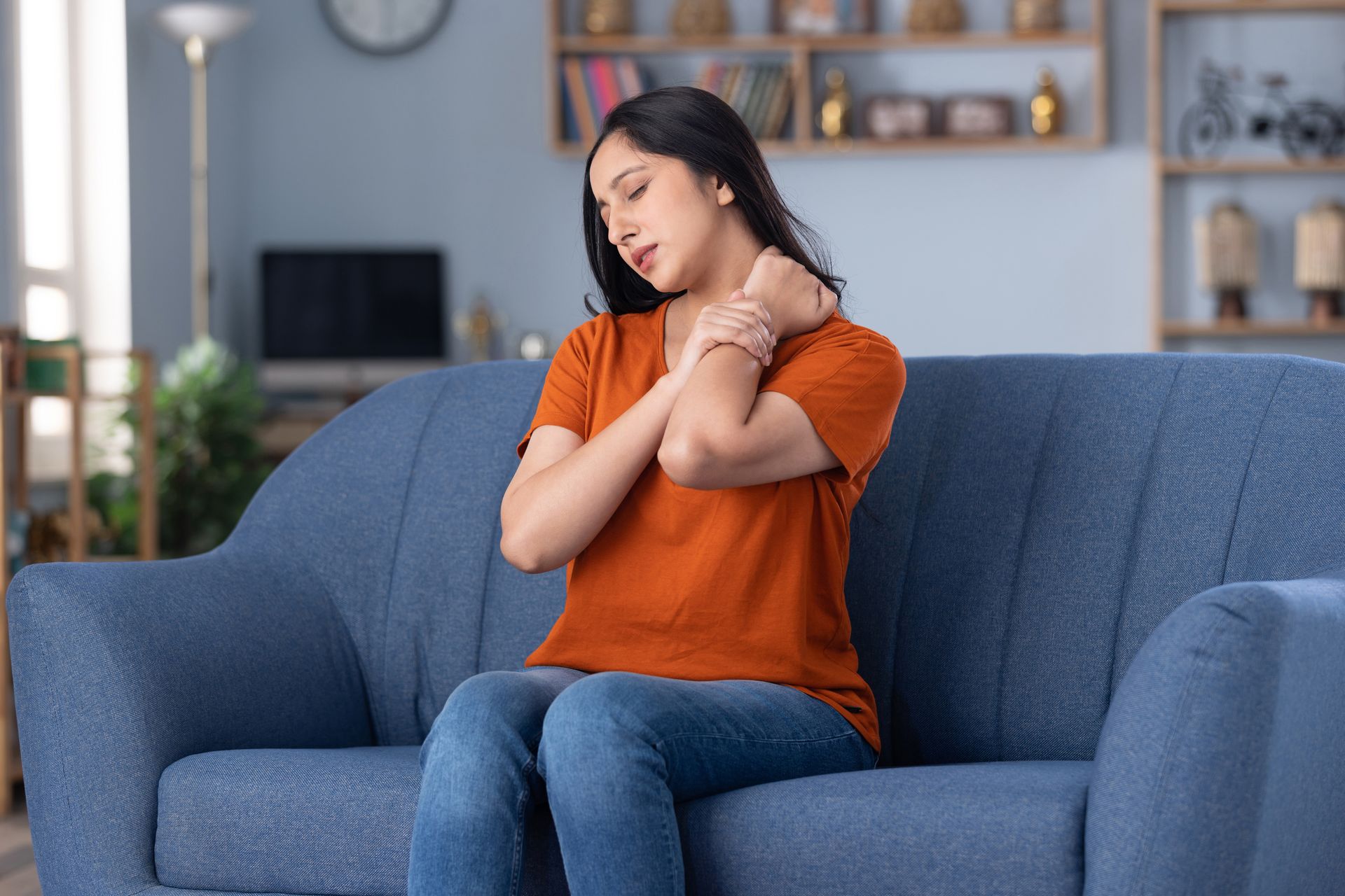 Woman experiencing shoulder and neck pain at home