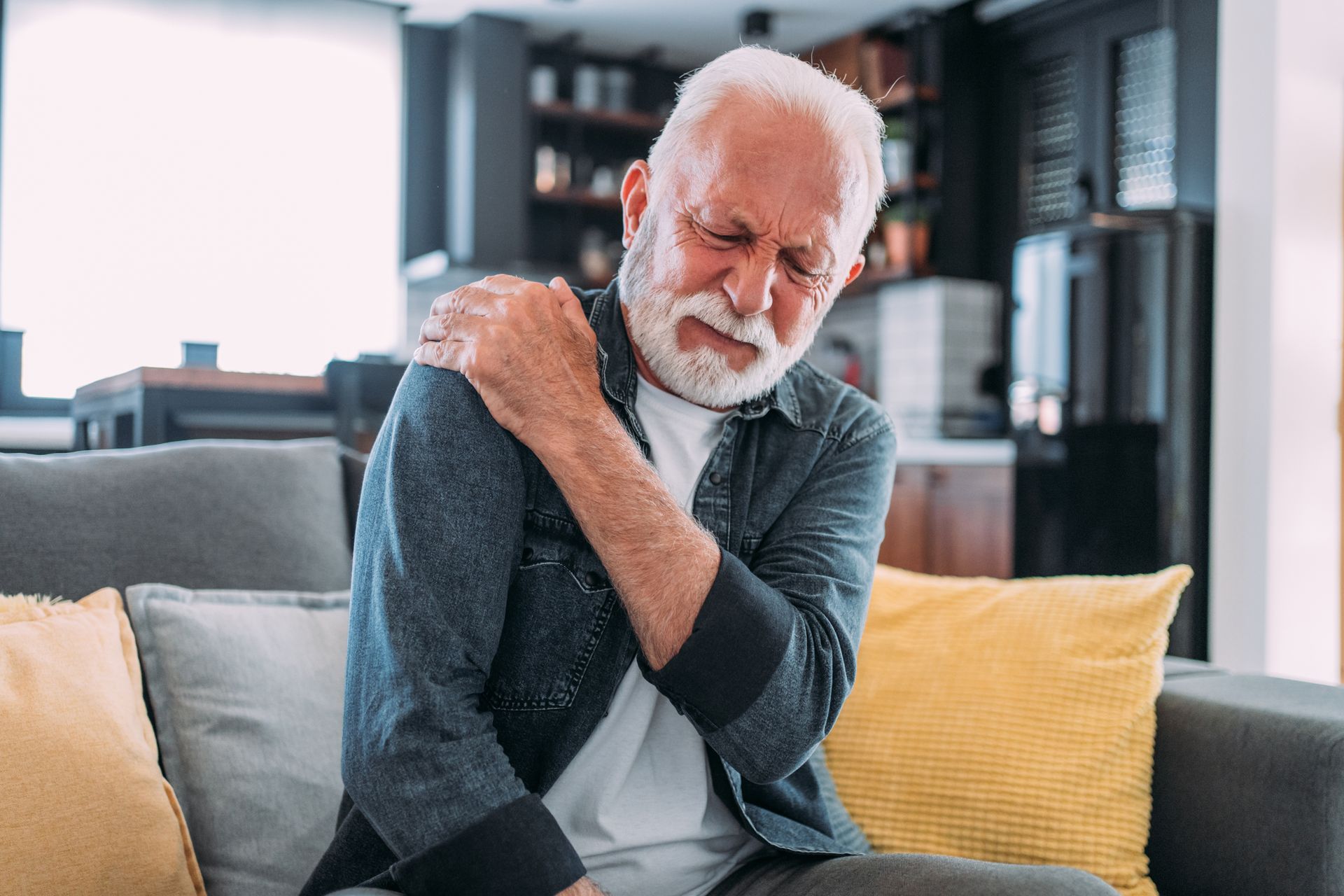 Older man experiencing shoulder pain at home