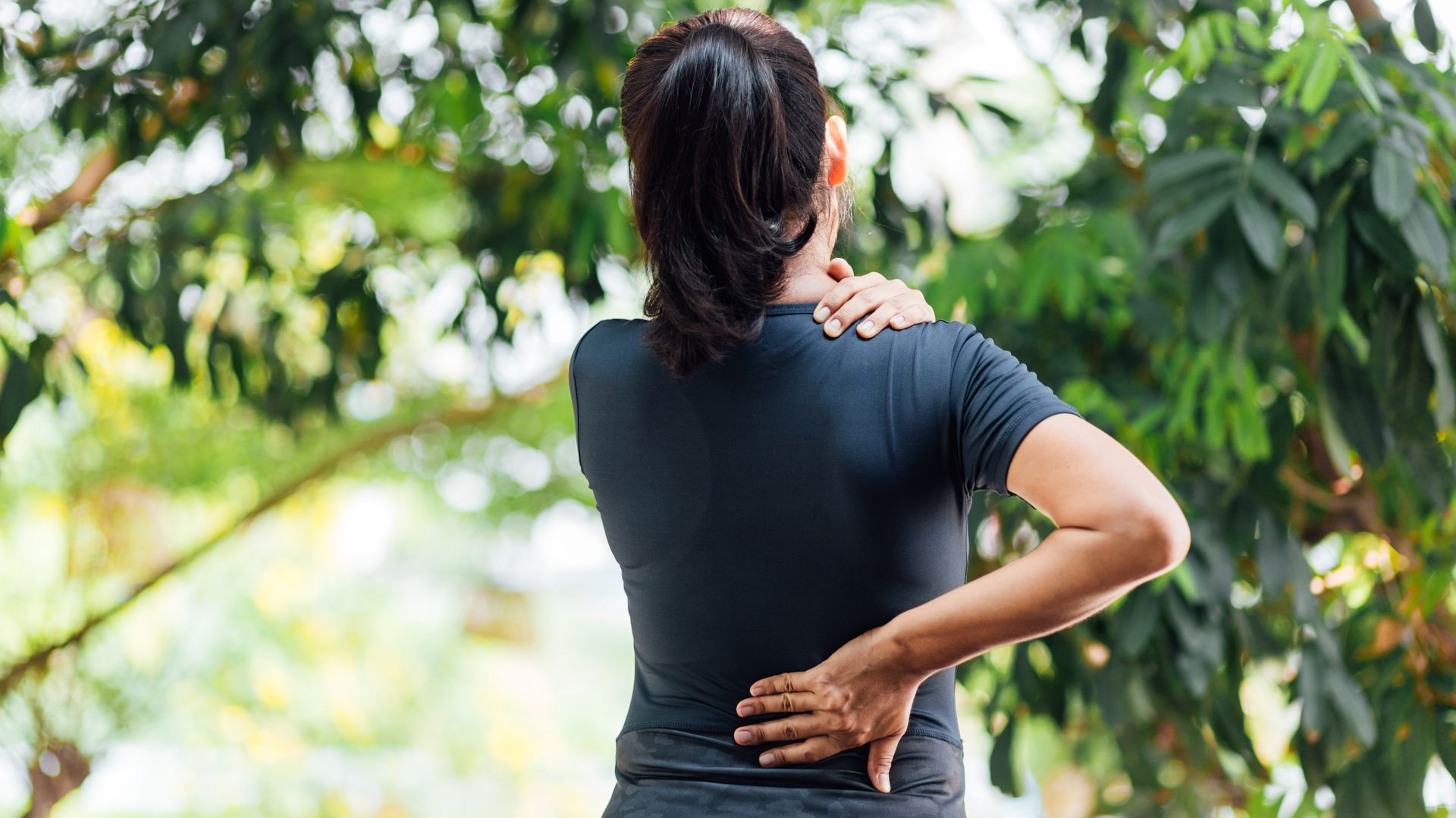 Woman experiencing neck and back pain outdoors