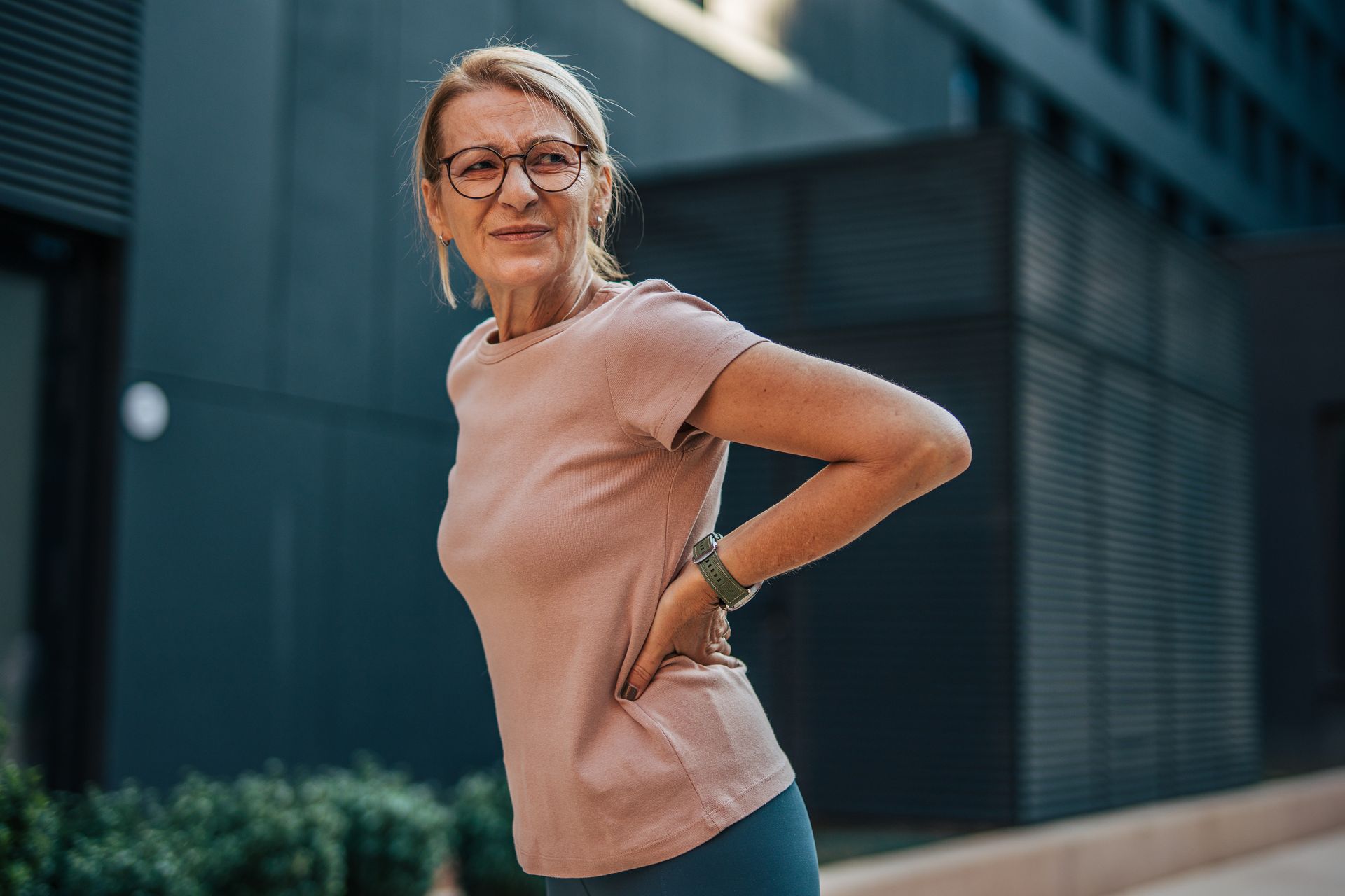 Woman experiencing lower back pain outdoors